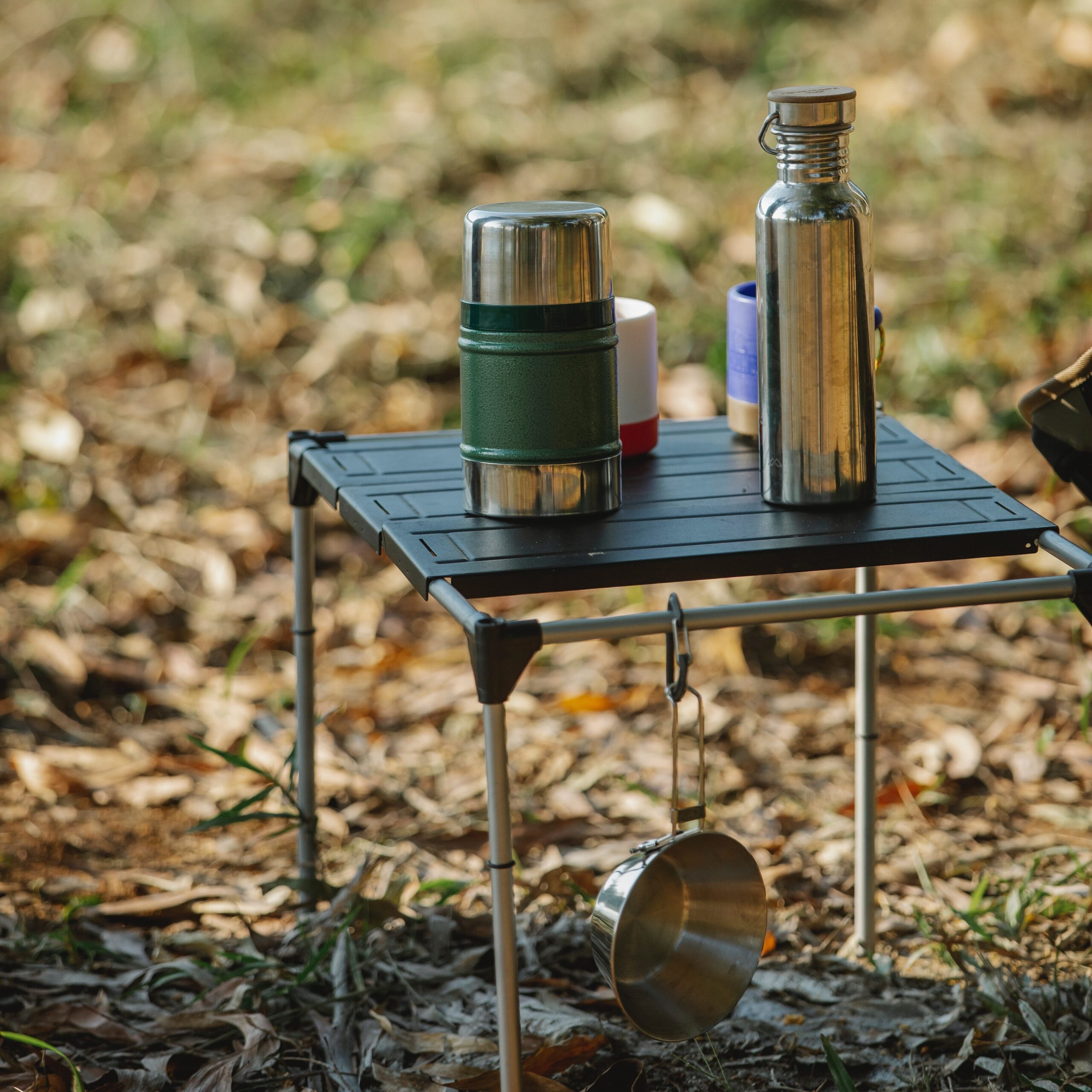 A portable camping table being with drinks on it. 