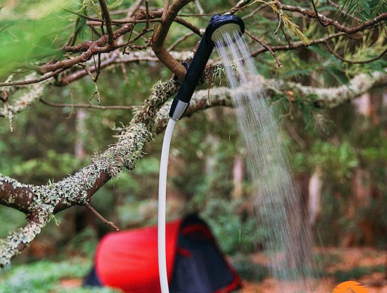 A Portable Shower hanging from a tree while on a camping trip.