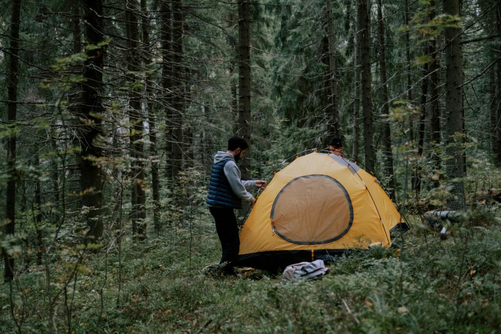 A man setting up his primitive camping tent alone